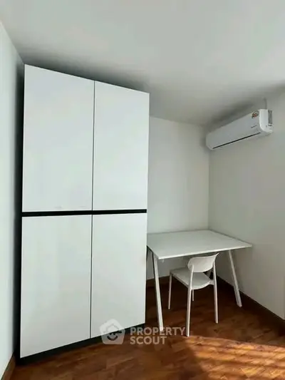 Modern study nook with sleek white furniture and air conditioning in a compact space.