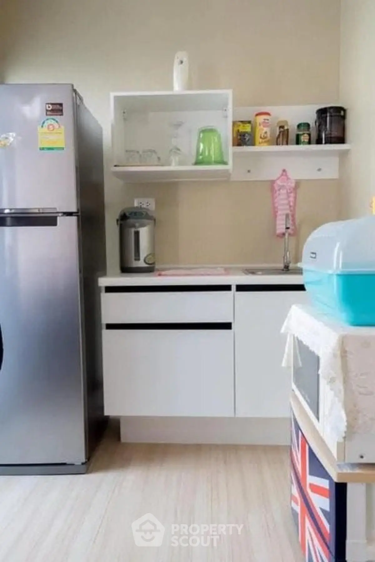 Modern kitchen with sleek cabinets and stainless steel fridge in compact layout.