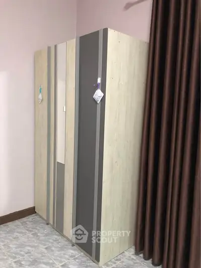 Modern wardrobe in a stylish bedroom with elegant curtains and tiled flooring.
