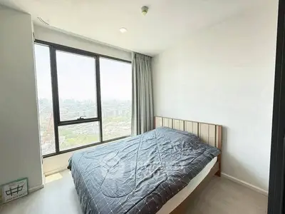 Modern bedroom with large window offering stunning city views, featuring a cozy bed and minimalist decor.