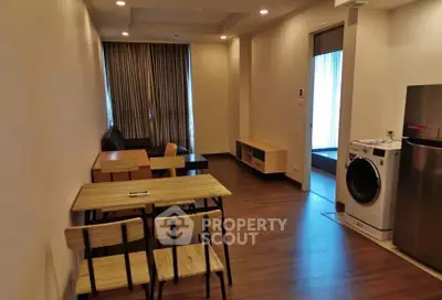 Modern apartment interior with dining area and washing machine, featuring wooden flooring and contemporary furniture.
