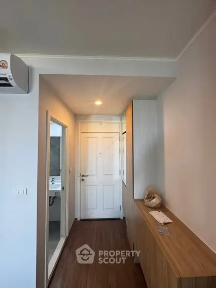 Modern apartment hallway with wooden flooring and sleek storage solutions.