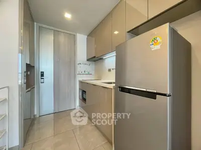 Modern kitchen with sleek cabinetry and stainless steel fridge in a stylish apartment.