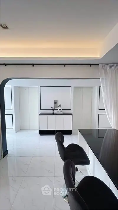 Modern minimalist living room with sleek black and white decor and stylish bar stools.
