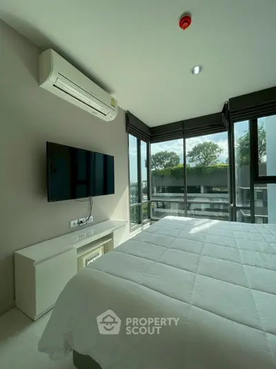 Modern bedroom with large windows and natural light in a contemporary apartment.
