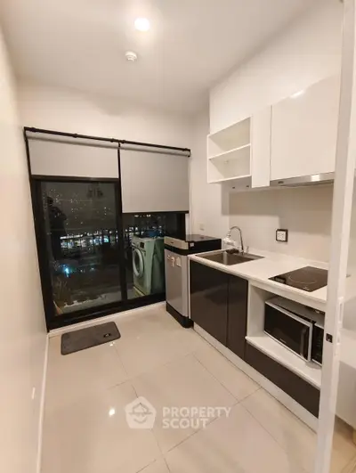 Modern kitchen with sleek appliances and city view, featuring a washing machine and microwave.