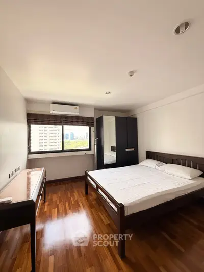 Spacious bedroom with wooden flooring and city view in modern apartment