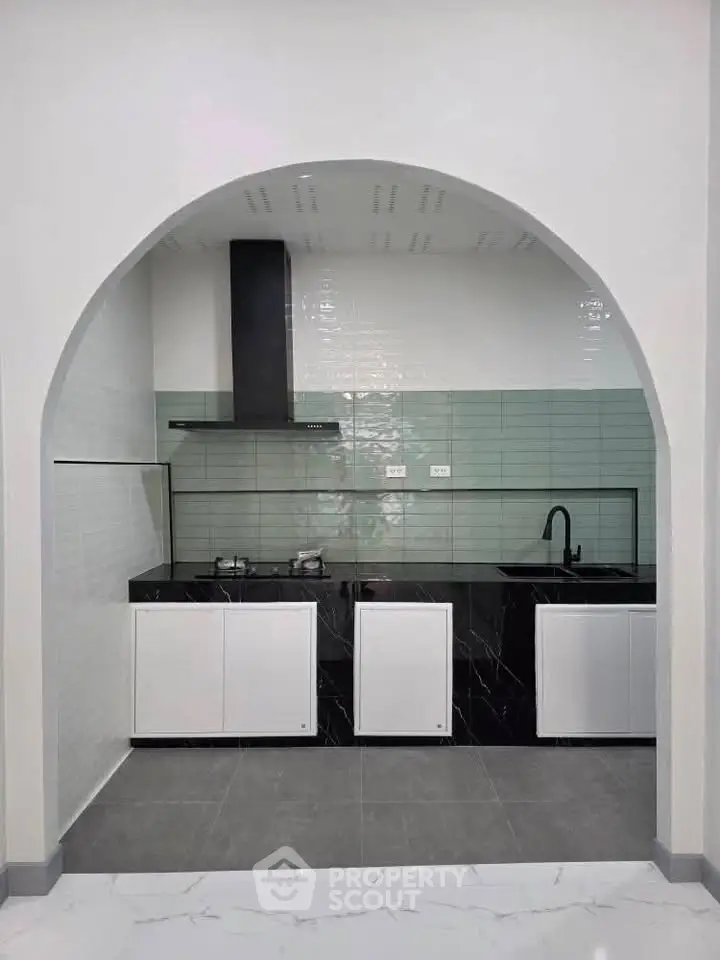 Modern kitchen with sleek black countertops and stylish archway entrance