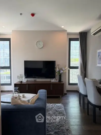 Modern living room with stylish decor, large windows, and a cozy seating area in a high-rise apartment.
