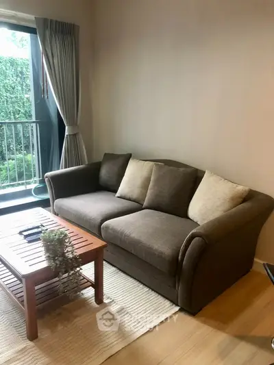 Cozy living room with plush sofa and garden view balcony, perfect for relaxation.