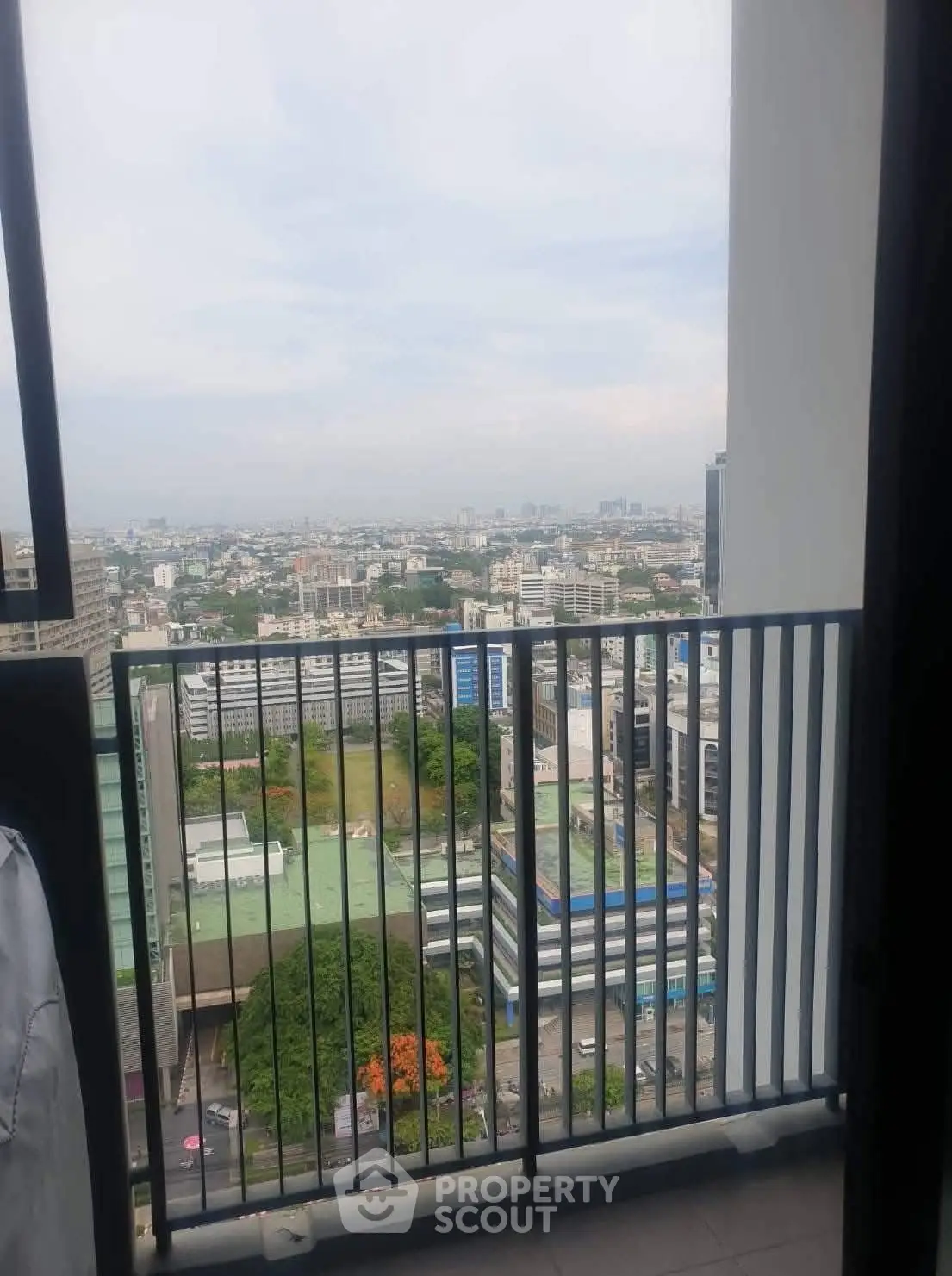 Stunning high-rise balcony view overlooking cityscape with lush greenery and urban skyline.