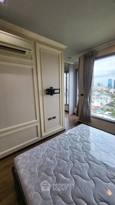 Spacious bedroom with city view and elegant design, featuring large windows and built-in air conditioning.