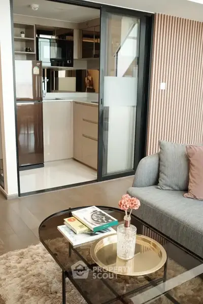 Modern living room with cozy sofa and open kitchen layout, featuring sleek appliances and stylish decor.