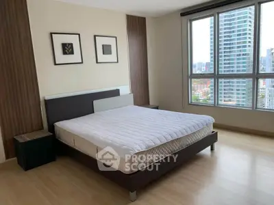 Spacious bedroom with large window and city view in modern apartment.