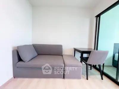 Modern living room with sleek gray sofa and compact dining area, perfect for urban living.