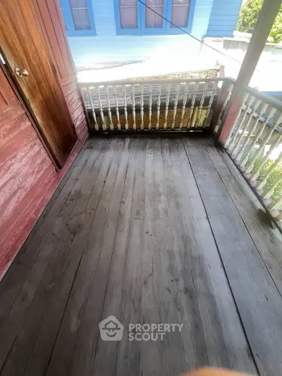 Charming wooden balcony with rustic railing and view of neighboring house, perfect for relaxation.