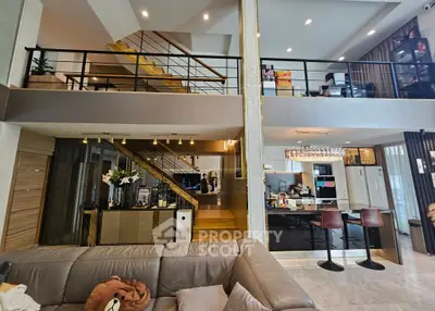Luxurious modern living room with open kitchen and mezzanine, featuring elegant decor and spacious layout.