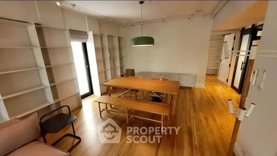 Spacious dining area with wooden flooring and modern lighting in a stylish apartment.