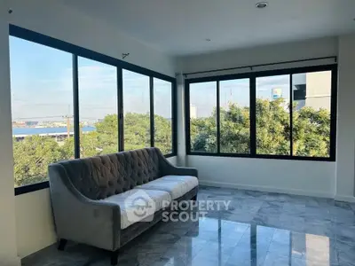 Spacious corner unit with large windows offering a stunning view, featuring a stylish sofa and elegant flooring.