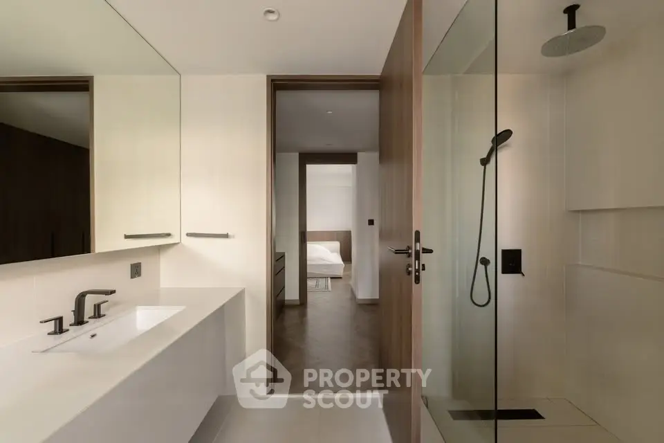 Modern bathroom with sleek fixtures and view into a stylish bedroom