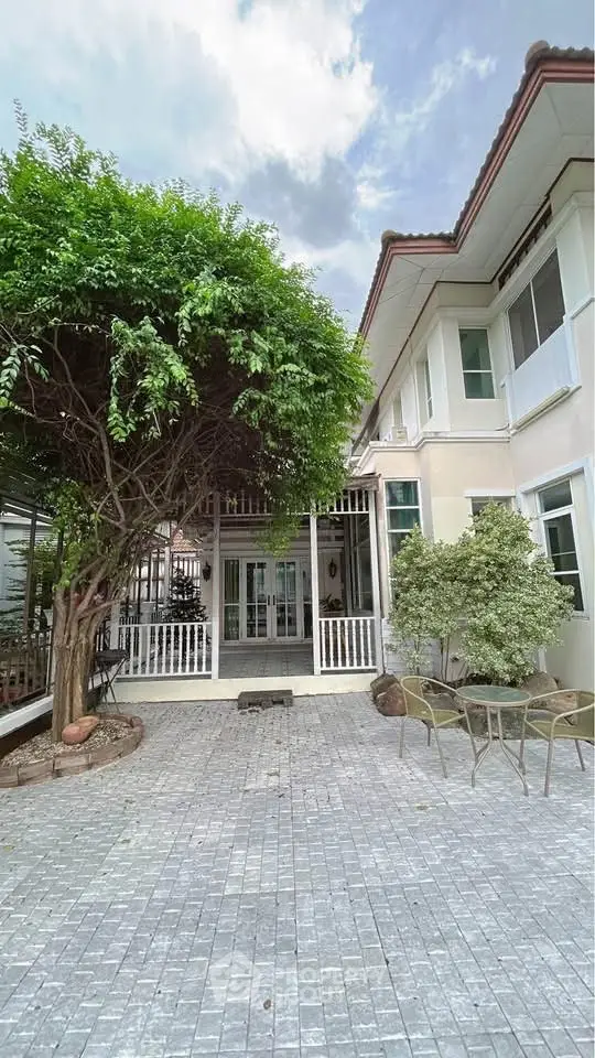 Charming two-story home with spacious patio and lush greenery, perfect for outdoor relaxation.