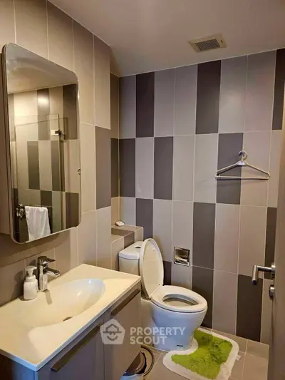 Modern bathroom with sleek design and stylish tiles, featuring a vanity and toilet.