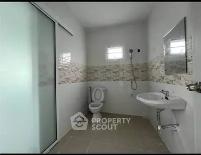 Modern bathroom with sleek design, featuring a shower, toilet, and sink in a spacious layout.