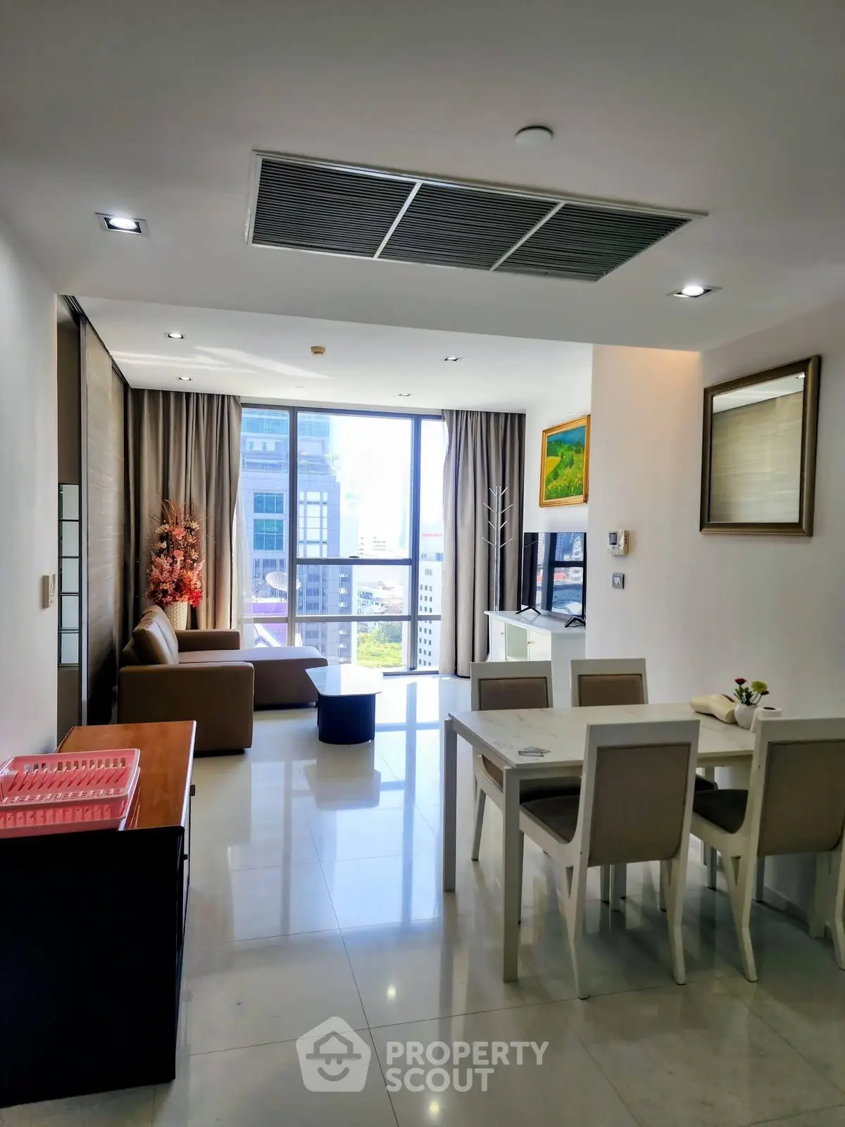 Modern living room with dining area and city view, featuring sleek furniture and large windows.