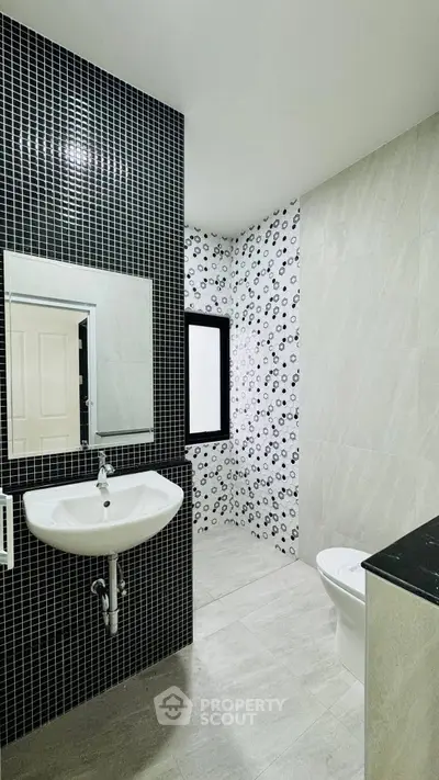 Modern bathroom with stylish black and white tile design and sleek fixtures.