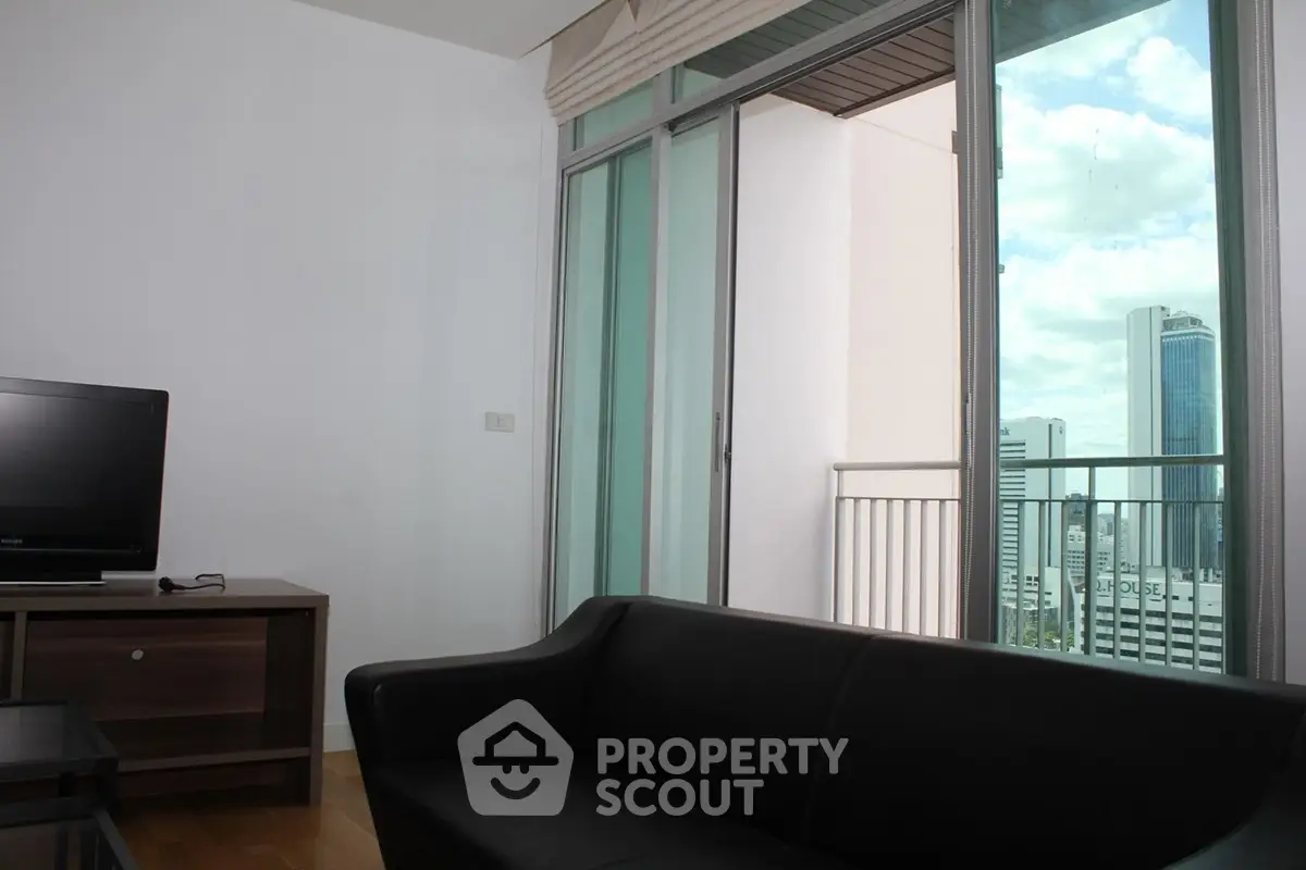 Modern living room with city view and balcony access in high-rise apartment.