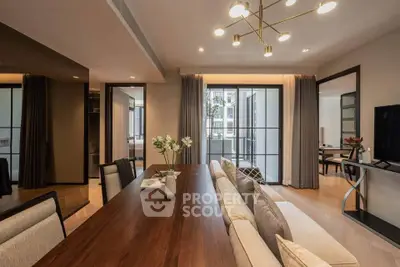 Elegant dining area with modern lighting and open layout, featuring a view of the balcony and stylish decor.