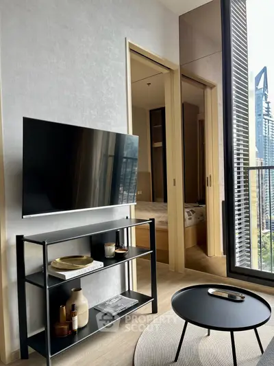 Modern living room with sleek TV stand, round coffee table, and balcony view in urban apartment.