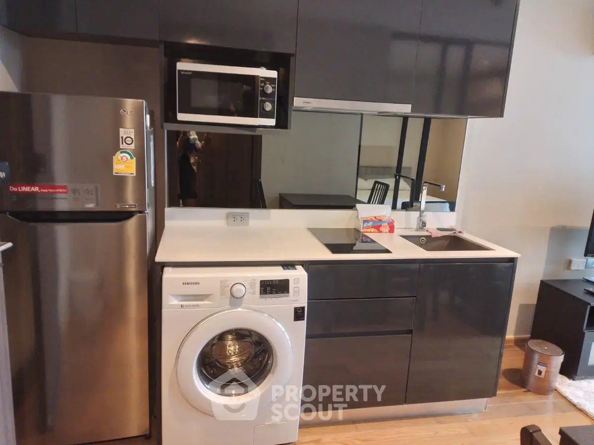 Modern kitchen with sleek appliances and washing machine in compact layout.