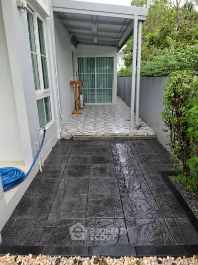 Charming outdoor patio with tiled flooring and lush greenery, perfect for relaxation and entertaining.