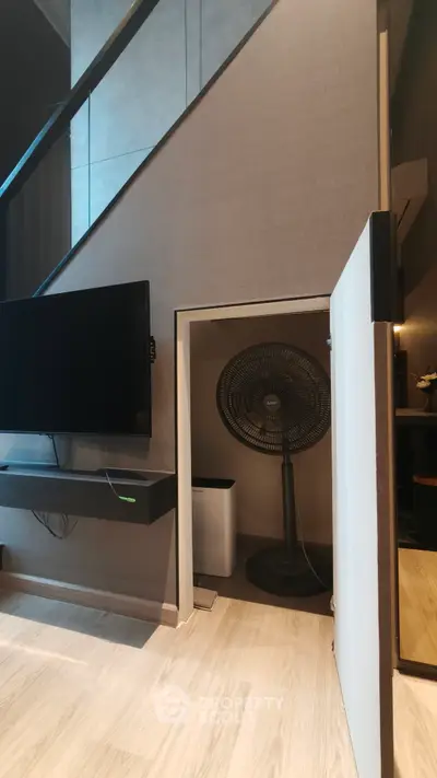 Modern interior with hidden storage under stairs featuring a fan and sleek TV setup.