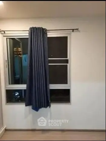 Minimalist room with window and blue curtains, ideal for cozy living space.