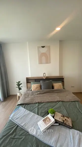 Modern bedroom with stylish decor and natural light, featuring a cozy bed and elegant artwork.