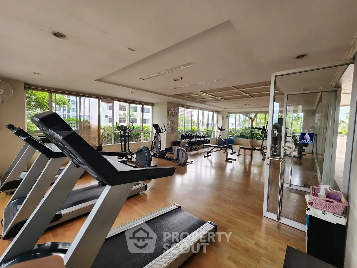 Spacious gym with modern equipment and large windows offering a bright and airy workout environment.