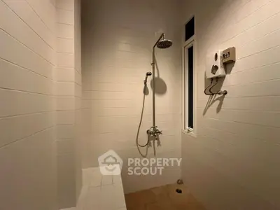 Modern minimalist bathroom with sleek shower and white tiled walls.