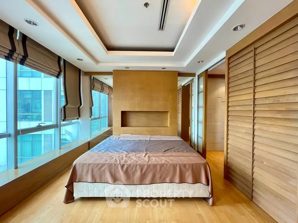 Luxurious bedroom with modern wooden accents and large windows in high-rise apartment.