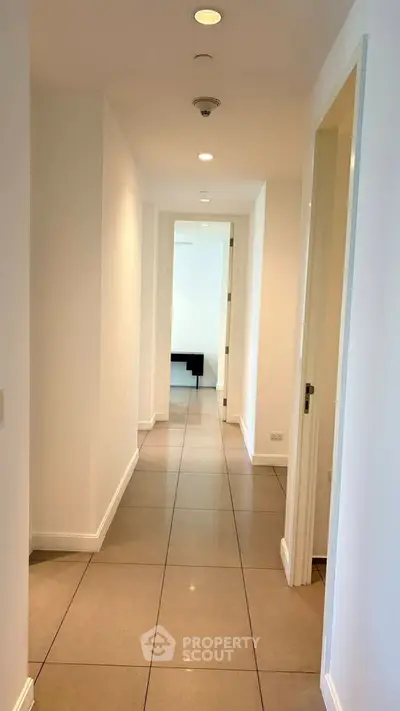 Bright and spacious hallway with modern tile flooring and recessed lighting.