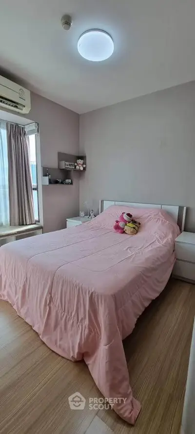Cozy bedroom with pink bedding and natural light, perfect for relaxation.