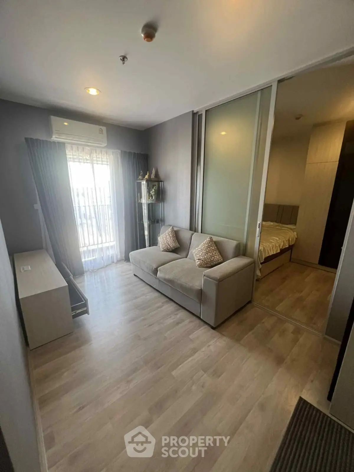 Modern living room with sliding glass doors leading to a cozy bedroom, featuring elegant decor and natural light.