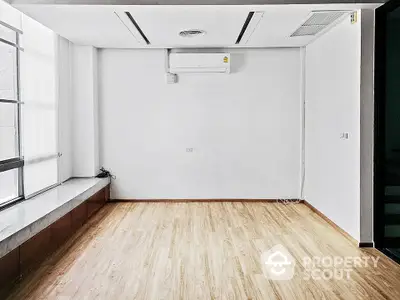 Spacious unfurnished room with wooden flooring and large window