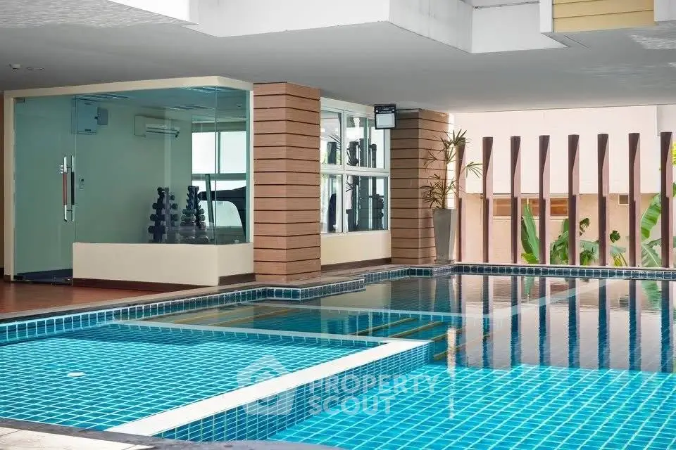 Luxurious indoor pool area with modern design and gym view, perfect for relaxation and fitness enthusiasts.