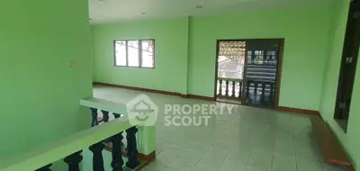 Spacious green-painted living area with tiled flooring and large windows.