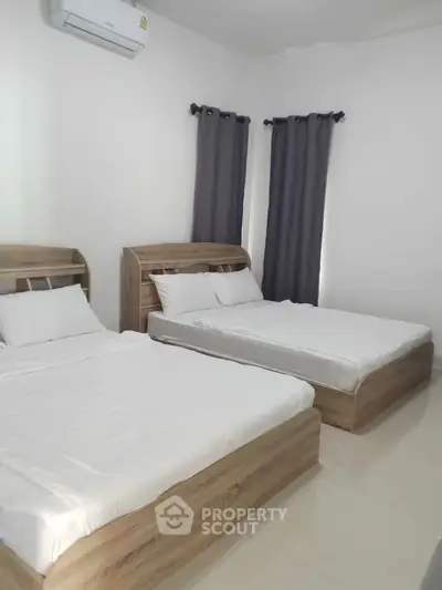 Spacious bedroom with two modern wooden beds and air conditioning.