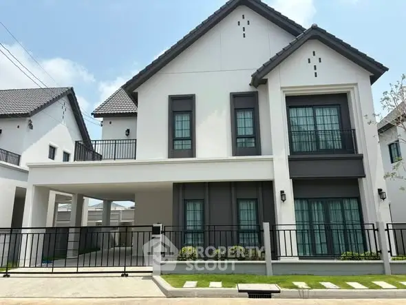 Modern two-story house with sleek design and spacious driveway in suburban neighborhood.