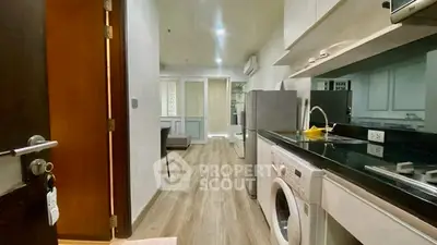 Modern kitchen with sleek appliances and washing machine in open layout apartment.