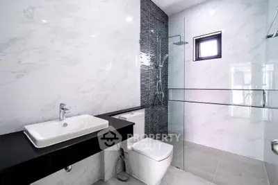Modern bathroom with sleek design, featuring a glass shower and elegant marble tiles.